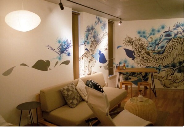 A living room with a sofa, a small round table, and a decorative wall mural.
