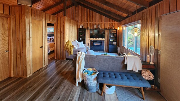 A cozy cabin interior with a wooden interior, a sofa, a bench, a fireplace, and a TV. - Upper Red Lake all season destination!  (Waskish)