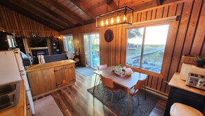A rustic kitchen with wooden cabinets, a dining table with chairs, and a large window offering a view of the outdoors. - Upper Red Lake all season destination!  (Waskish)
