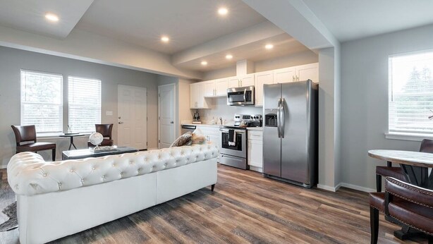 Una cocina moderna con armarios blancos, electrodomésticos de acero inoxidable y piso de madera.