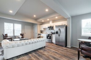 Una cocina moderna con armarios blancos, electrodomésticos de acero inoxidable y piso de madera.