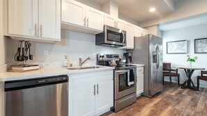 Una cocina moderna con armarios blancos, electrodomésticos de acero inoxidable y piso de madera.
