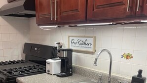 A kitchen with wooden cabinets, a stainless steel sink, a stove, a toaster, and a coffee maker. - Luxurious NYC Retreat / Central Location / Wi-Fi (Freeport)