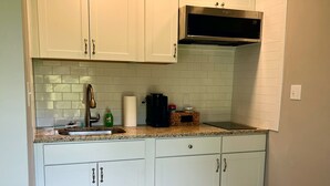 A kitchen with white cabinets, a stainless steel range hood, and a granite countertop.