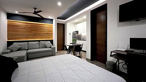 Une chambre d’hôtel moderne dotée d’un grand lit, d’un canapé, d’une table à manger avec des chaises, d’un coin cuisine et d’une télévision.