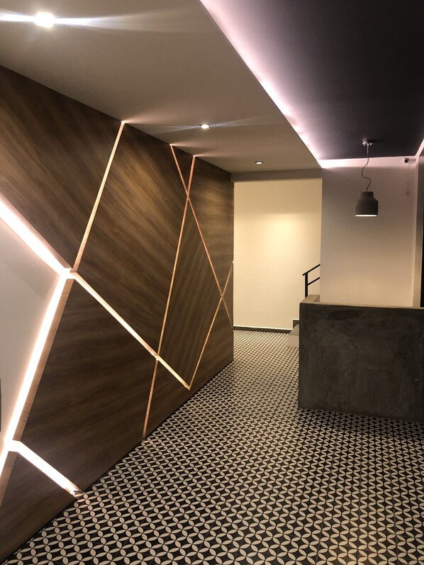 Un espace d’accueil moderne, avec un décor mural aux motifs géométriques, un sol à motifs et un comptoir d’accueil minimaliste.