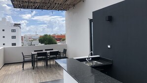Un espace cuisine extérieur moderne, doté d’un coin repas et offrant une vue sur le paysage urbain.