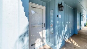 A blue exterior with a white door, a welcome mat, and a sign that reads 'Sandy Feet Welcome Outside.' - Beach Service Included, Pet Friendly! Pickle Ball Courts , CLM 11A! (Destin)