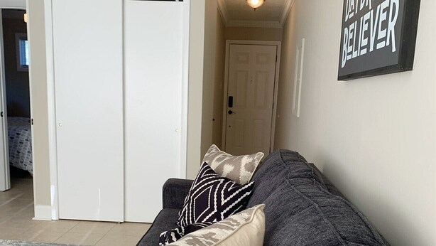 A living room with a grey sofa, patterned pillows, and a 'Daydream Believer' sign on the wall. - Capital City Condo #4 (Frankfort)