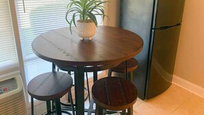 A dining area with a round table, four chairs, a potted plant, and a refrigerator. - Capital City Condo #4 (Frankfort)