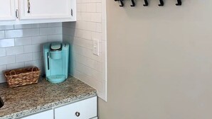A kitchen with white cabinets, a coffee maker, and a hanging plant on a shelf. - Capital City Condo #4 (Frankfort)