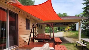 Un espace extérieur abrité avec des sièges, une balançoire, un banc et une table de pique-nique.