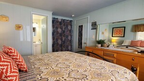 Une chambre à coucher comprenant un lit, une table de chevet, une commode et un miroir.