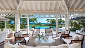 A covered outdoor lounge area with seating, a pool, and a view of the ocean. - The Great House | Beach Front - Located in  Exquisite St. Peter with Private Pool (Mullins)