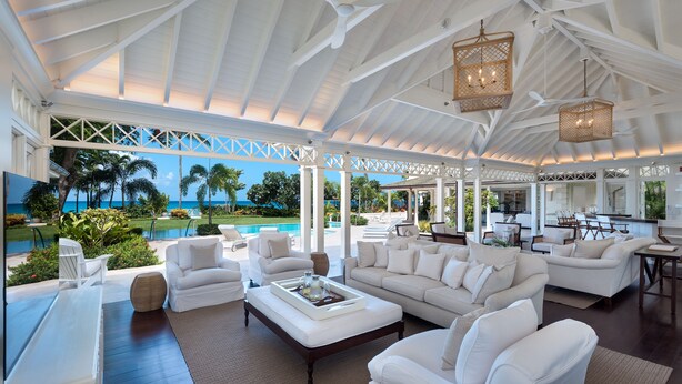A spacious living area with white furniture, a pool view, and a covered patio. - The Great House | Beach Front - Located in  Exquisite St. Peter with Private Pool (Mullins)