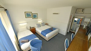 A hotel room with two beds, a desk, a chair, and a bathroom visible through an open door.