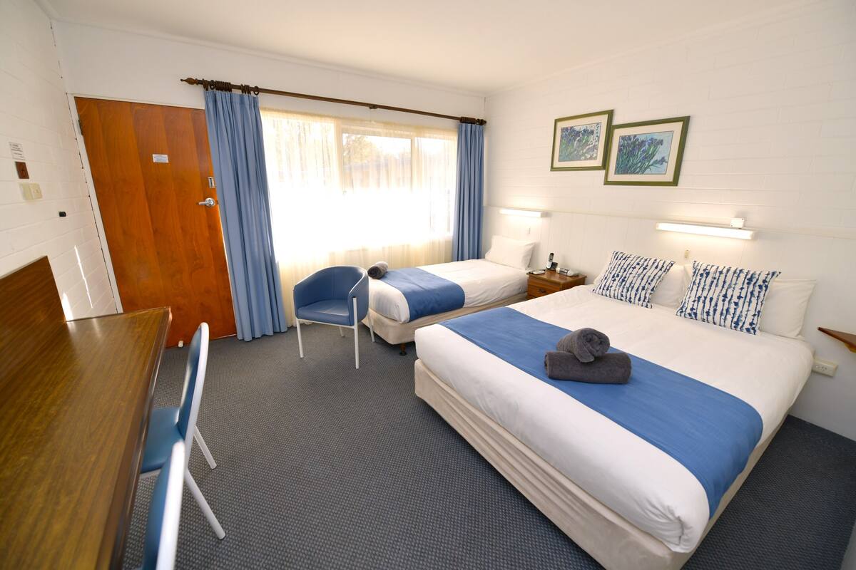 Une chambre d’hôtel avec deux lits, un bureau et une chaise.