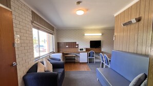 A compact living space with a kitchenette, a sofa, a dining table, and a TV.