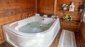 A wooden cabin with a large, white, freestanding hot tub.