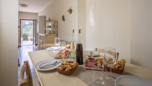 A dining table set with plates, glasses, and various dishes, including bread and charcuterie, in a room with arched ceilings and a view of the outdoors.