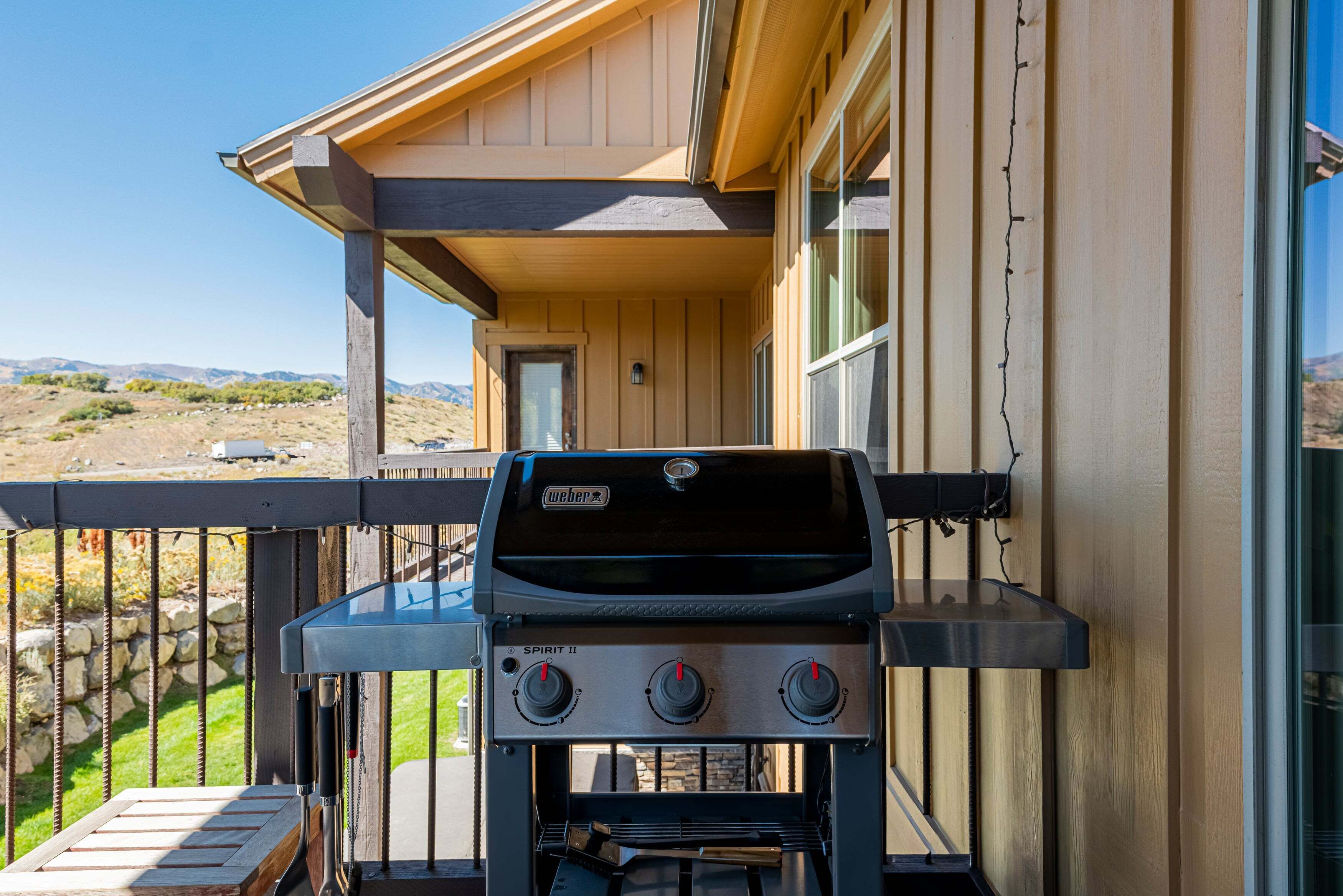Una parrilla Weber Spirit II en un balcón con vistas a un paisaje montañoso.