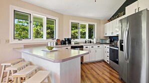 Cozinha moderna com ilha central, eletrodomésticos de aço inoxidável e amplas janelas.