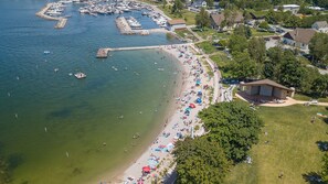 Vista aérea de uma praia com barcos, um cais e um edifício com gramado.