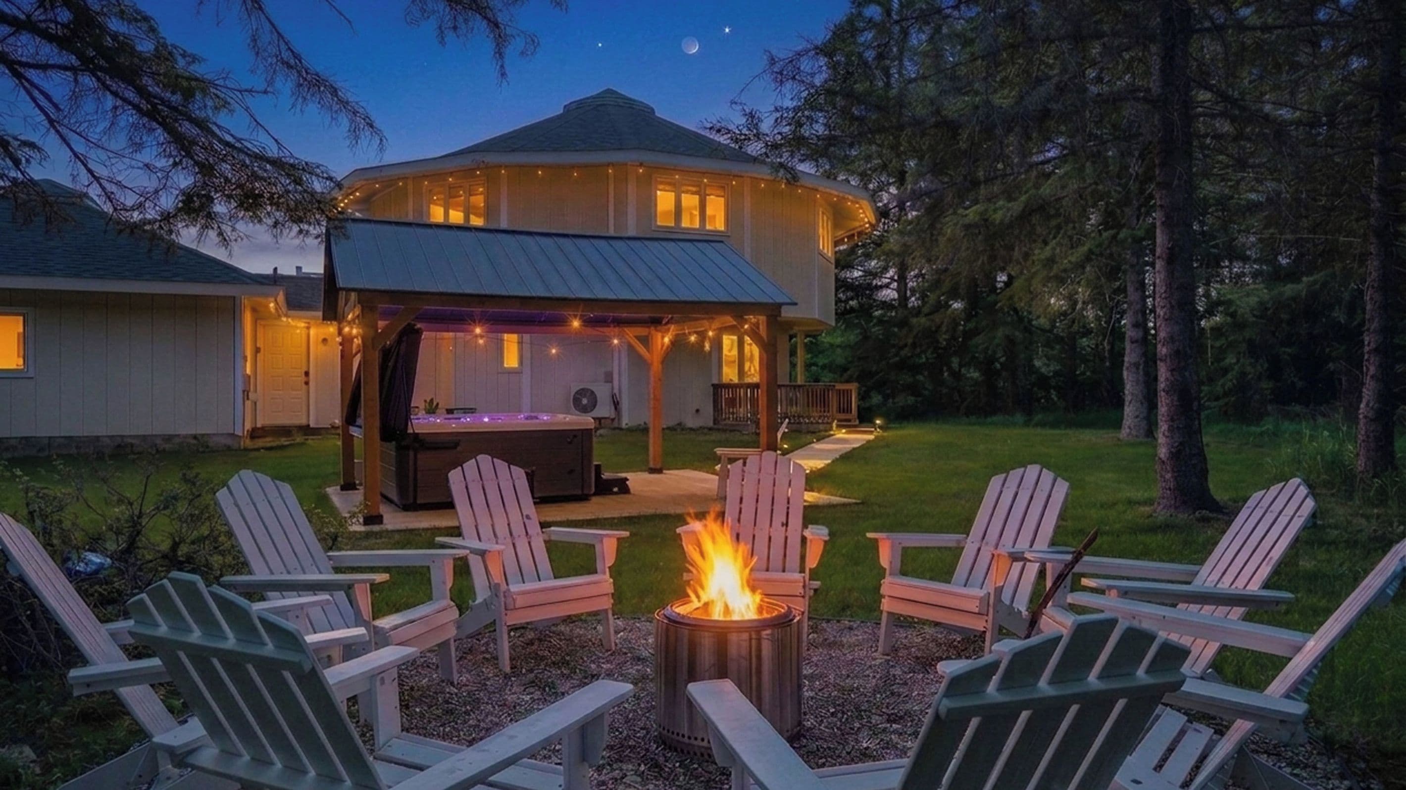 A house with a covered outdoor area, a fire pit, and Adirondack chairs.
