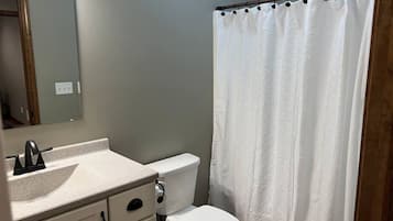 A bathroom with a toilet, sink, and shower curtain.