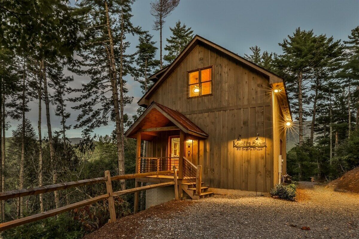 Una cabaña de madera con un porche, una escalera y un letrero que dice 'Kittie Barn'.