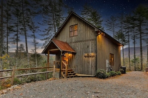 A rustic wooden cabin with a porch, a staircase, and a sign that reads 'King's Barn.'
