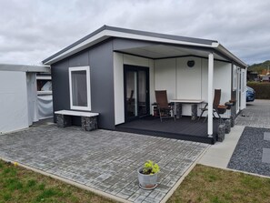 Una casa moderna con un porche cubierto, comedor y un pequeño jardín.