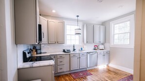 Une cuisine moderne avec des meubles blancs, un plan de travail en marbre et un revêtement de sol en bois.