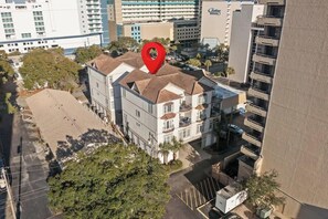 An aerial view of a hotel with a red location pin, surrounded by other buildings and trees.