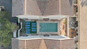 Ein Luftbild zeigt ein Hotel mit Pool auf dem Dach, mehreren Balkonen und einem Innenhof.