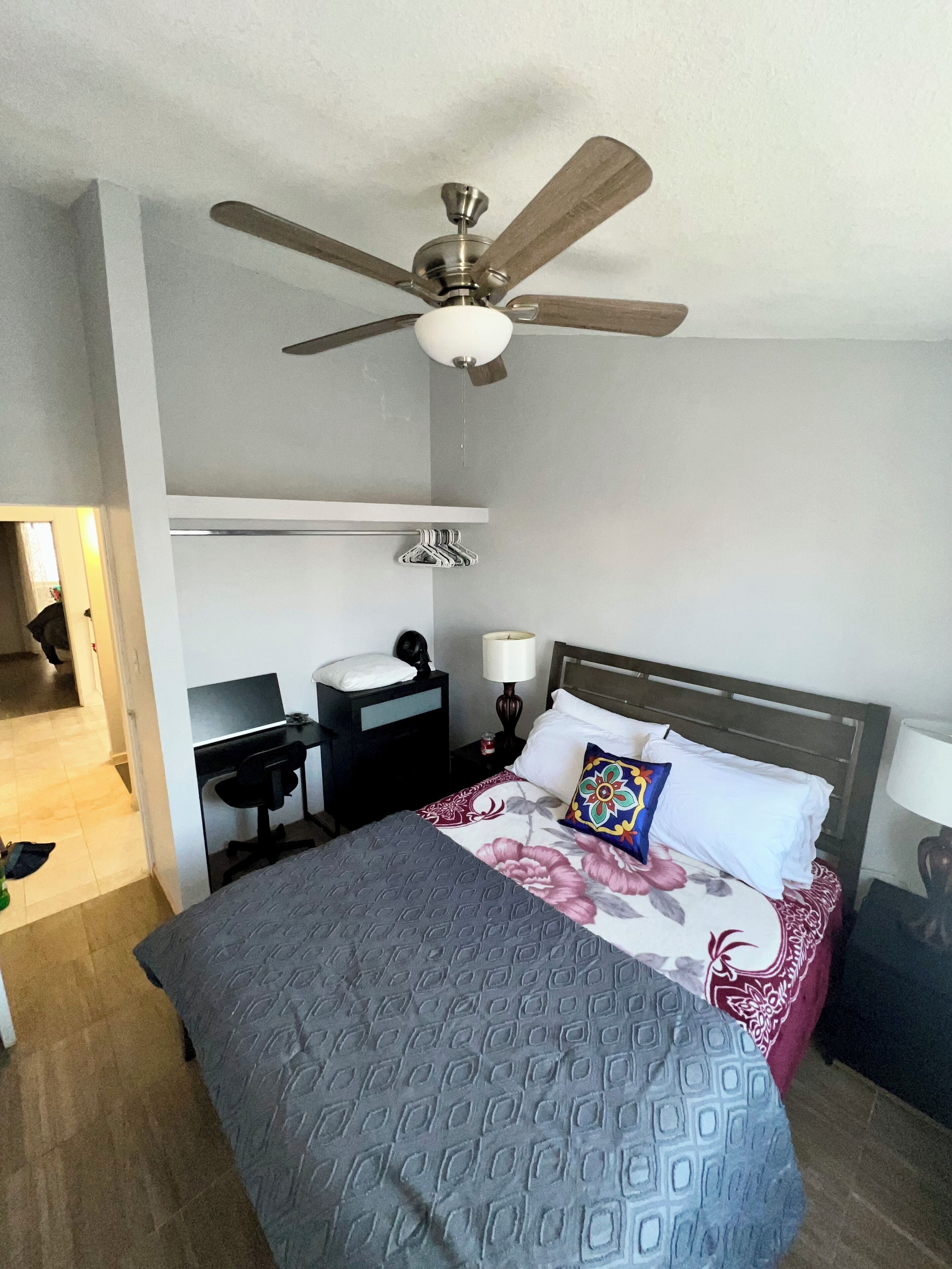 Une chambre d’hôtel équipée d’un lit, d’un bureau, d’une chaise et d’un ventilateur de plafond.
