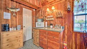 Cocina de cabaña de madera con microondas, cafetera y armarios de madera.