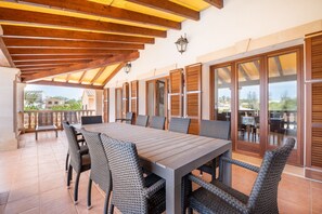 Enjoy meals al fresco at this outdoor dining area with a long table and comfortable wicker chairs.