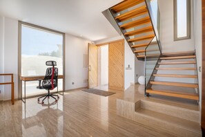 Enjoy a spacious room with a large window offering a view of the outdoors, a glass staircase, and a minimalist design.
