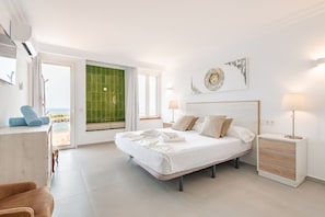 A modern bedroom with a bed, bedside tables, a chair, and a view of the sea. - Villa Enderrosall in Porto Cristo (Porto Cristo)