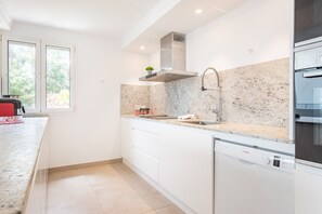 A modern kitchen with white cabinetry, a stainless steel range hood, and a Bosch dishwasher.