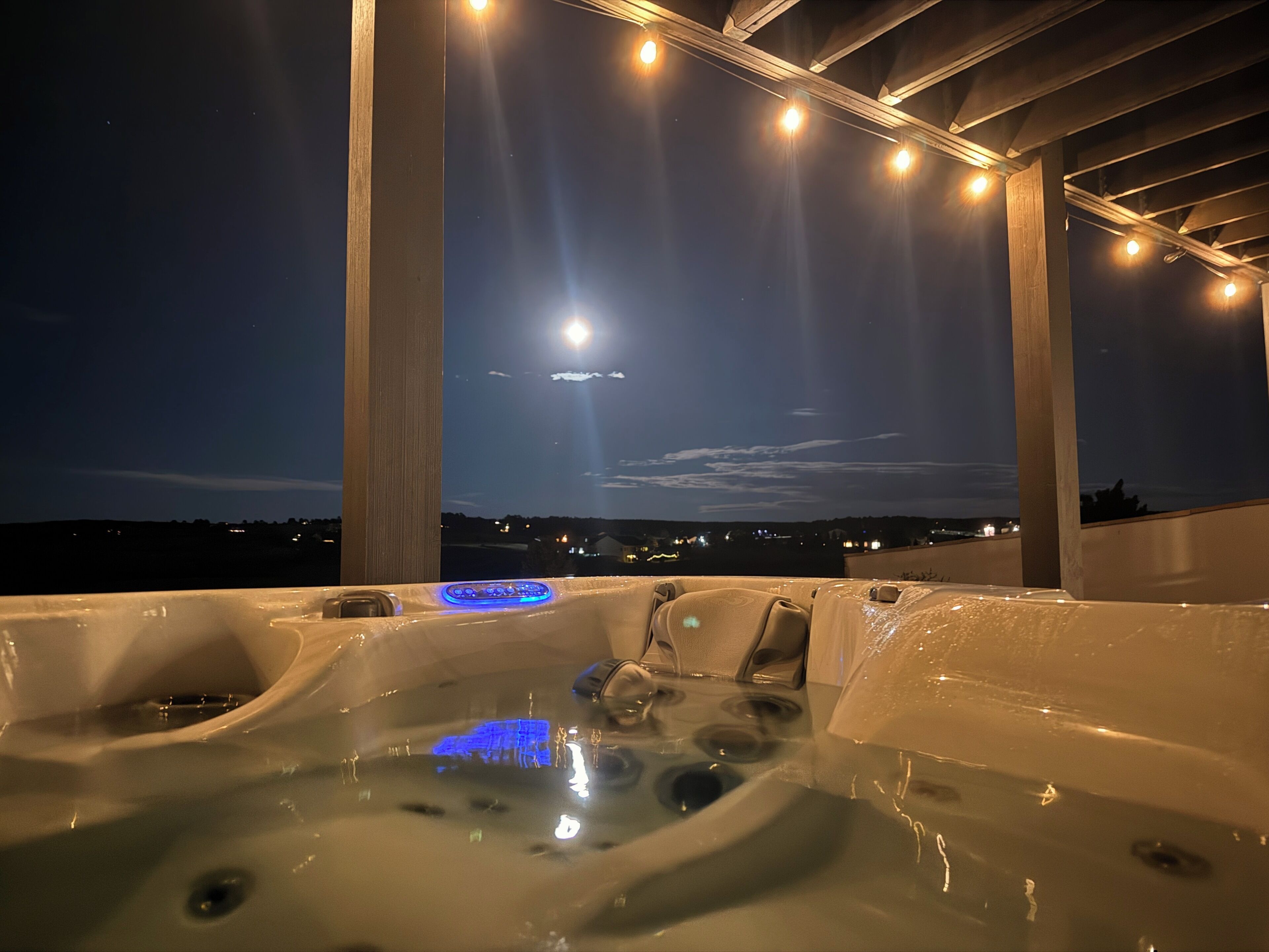 A hot tub area with a view of the night sky and a distant cityscape.