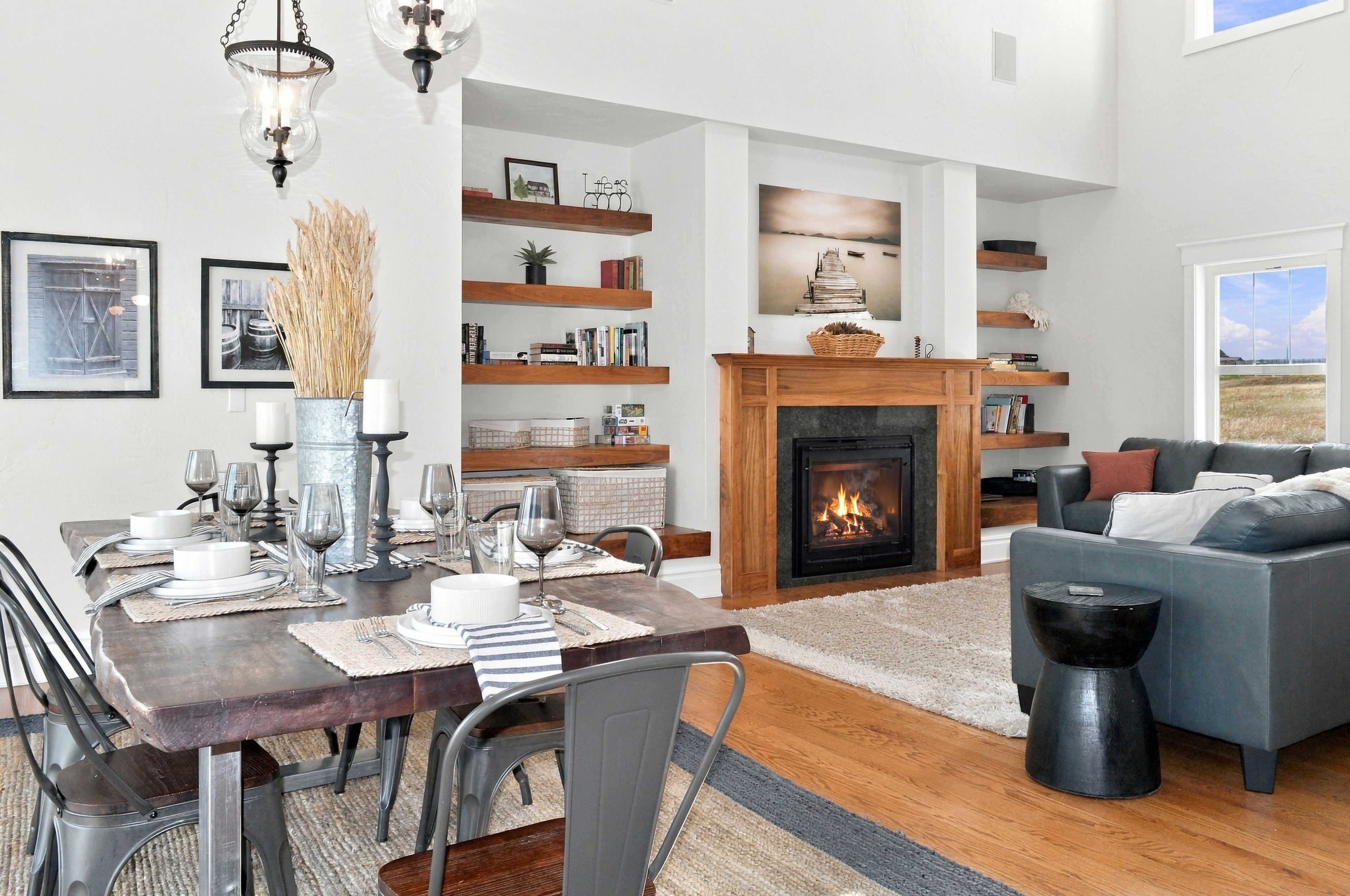 A modern living room with a fireplace, dining area, and a view of the outdoors.