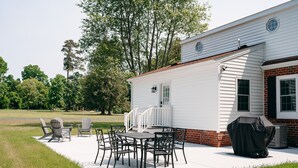 En terrasse med udendørs møbler, grill og et overdækket grillområde.