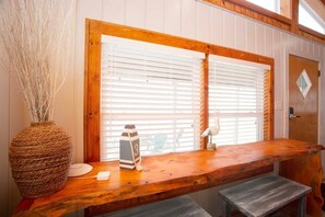 Un coin bar en bois au design rustique, un panier tressé, une horloge et une porte dotée d’une fenêtre en forme de losange.