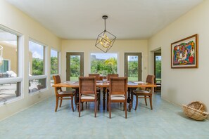 Uma área de refeições com uma mesa grande, cadeiras e um lustre.