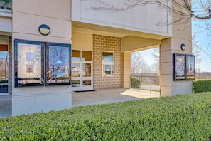 Stunning building with a symmetrical facade, featuring two large artworks and a beautifully manicured hedge.
