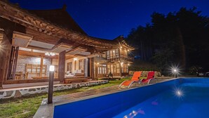 A traditional wooden building with a pool and lounge chairs.