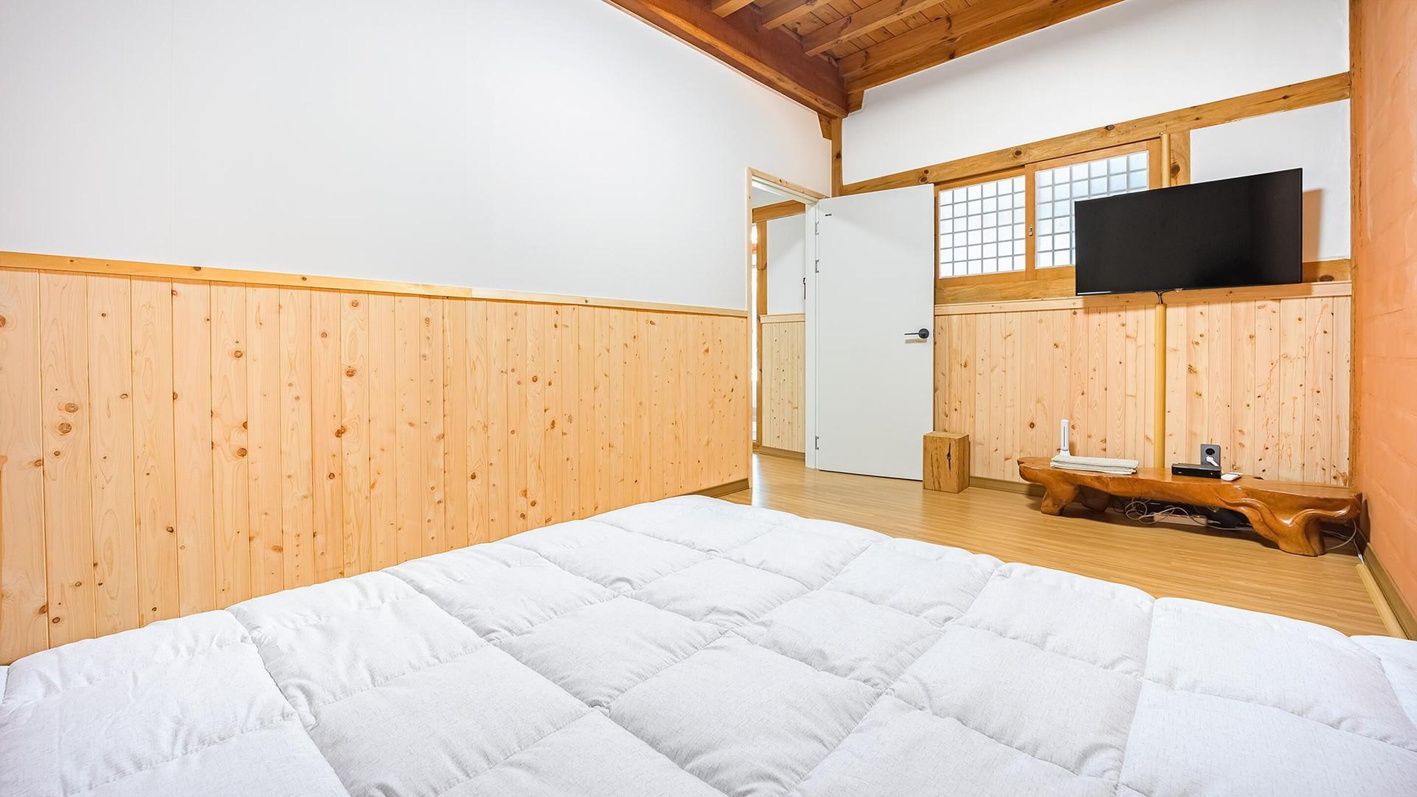 Ein Schlafzimmer mit einem Bett, Holzwänden, einem Fernseher und einem kleinen Holztisch.