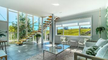 Relax in a spacious living area with a panoramic view of the surrounding landscape, featuring a comfortable sofa, coffee table, and chair.